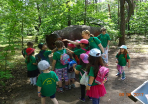 Dzieci oglądają postać dinozaura, głaszczą go.